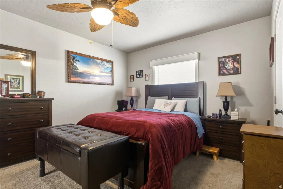 Bedroom with light colored carpet, a ceiling fan, and a textured ceiling