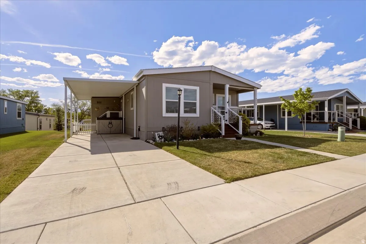 Manufactured / mobile home featuring a front yard, concrete driveway, a carport, and a porch