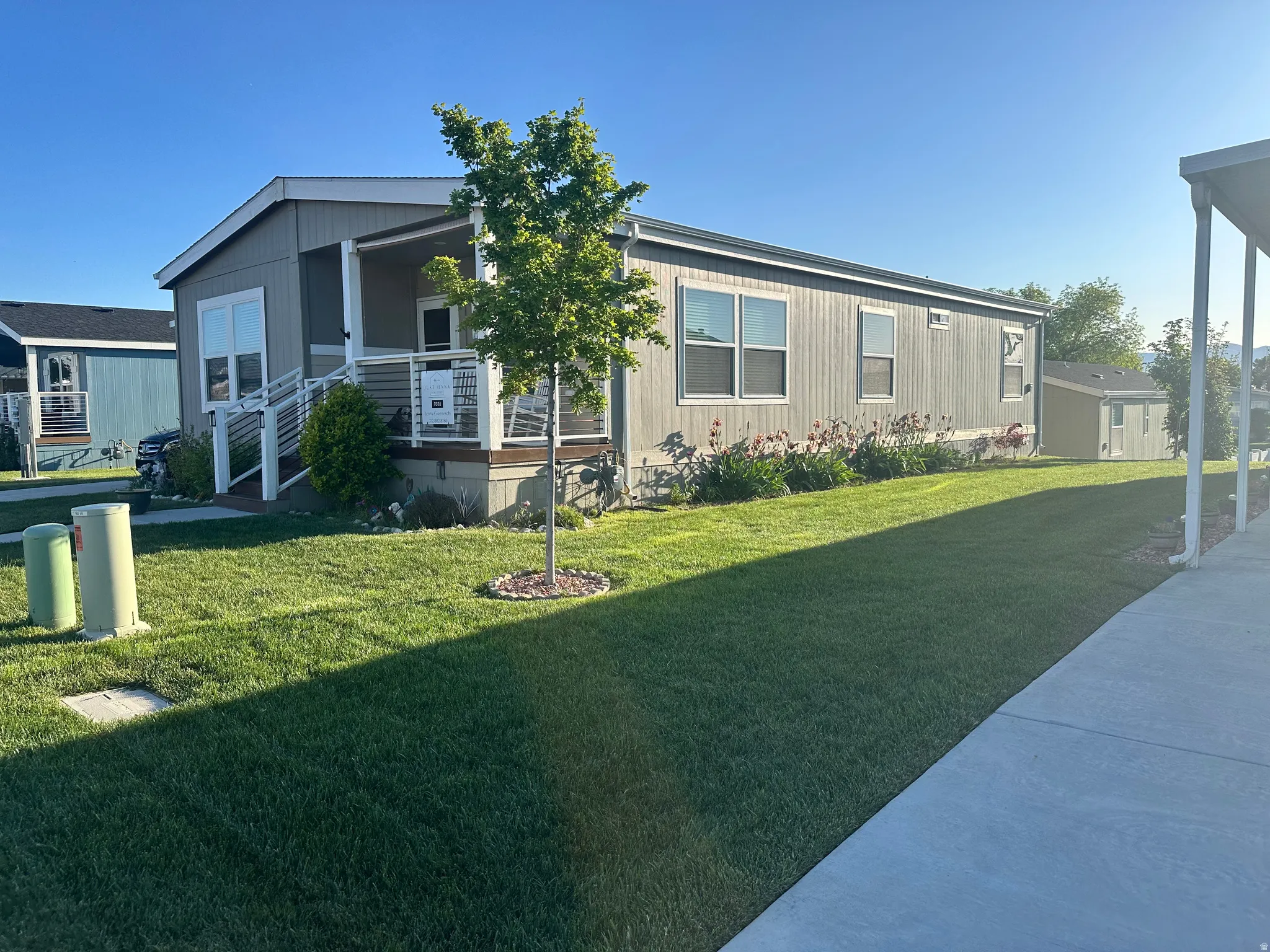 Gray siding exterior with multiple windows, an inviting covered porch, and a dedicated entry ramp