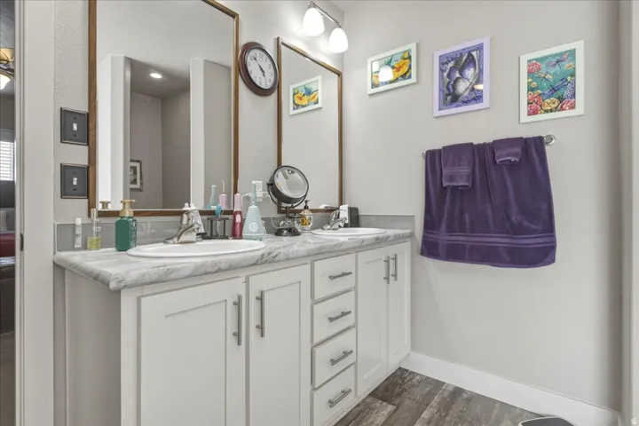 Full bathroom with double vanity and dark wood finished floors