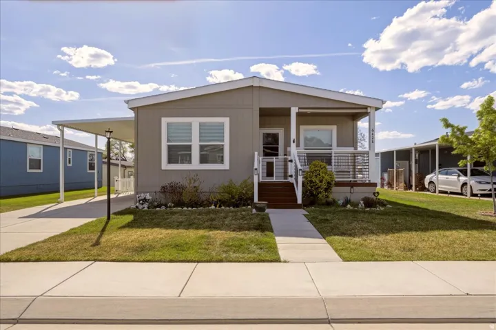 Manufactured / mobile home with covered porch, a carport, a front lawn, and driveway