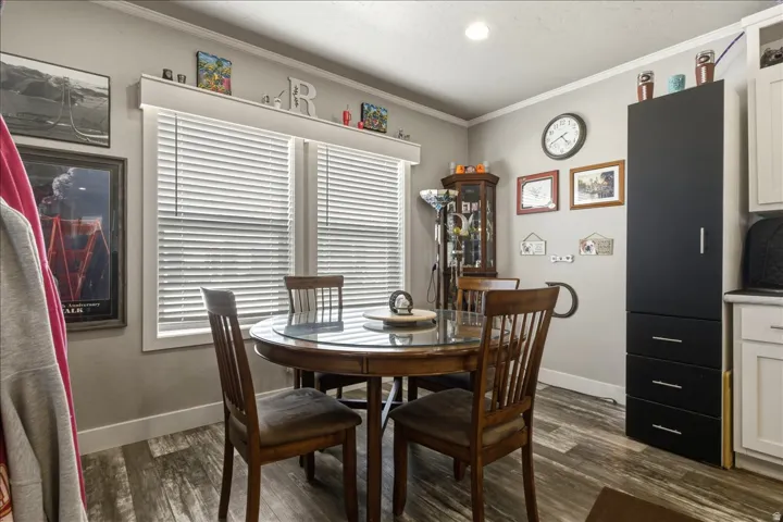 Dining space with dark wood-type flooring and crown molding