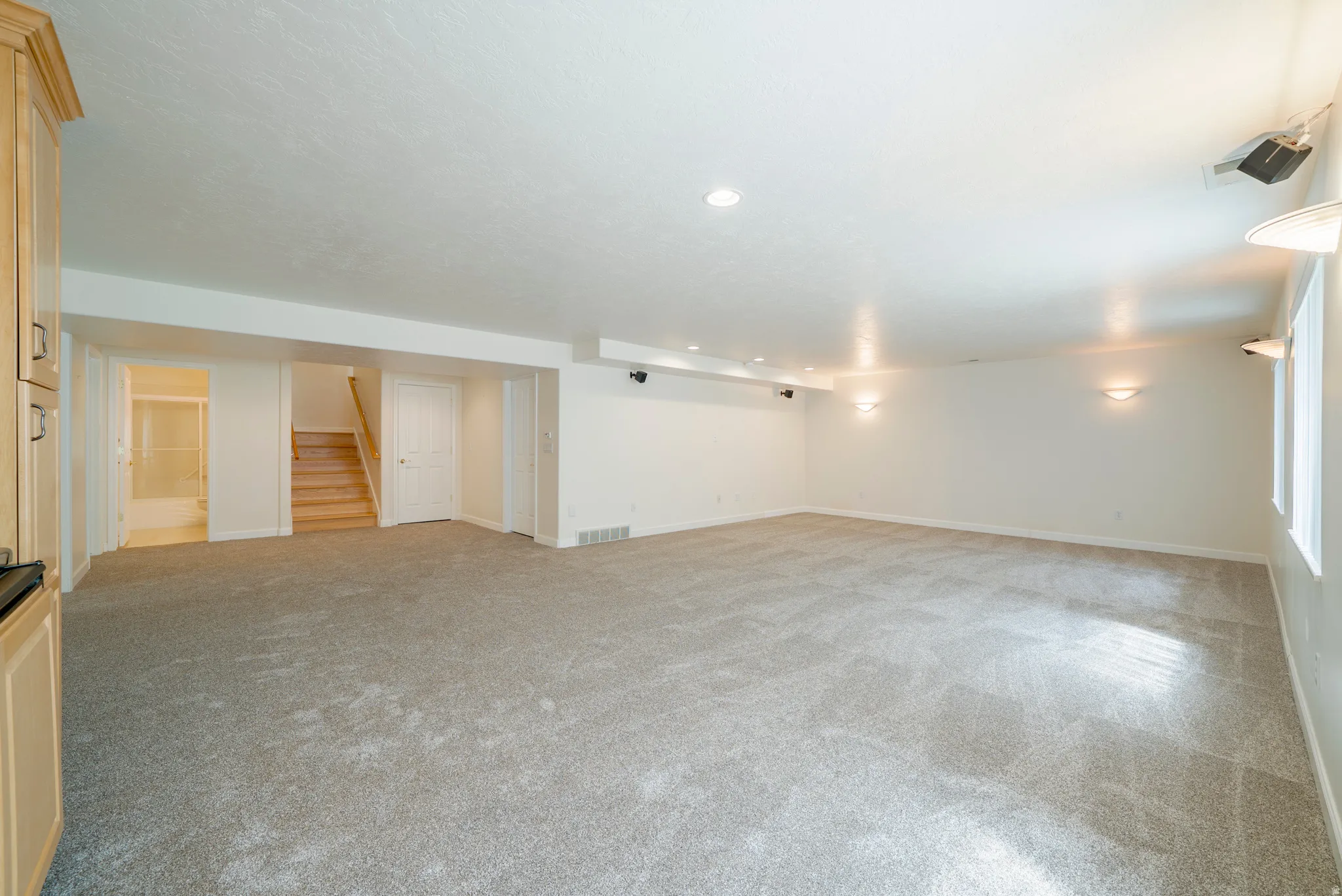 Unfurnished living room with light colored carpet and recessed lighting