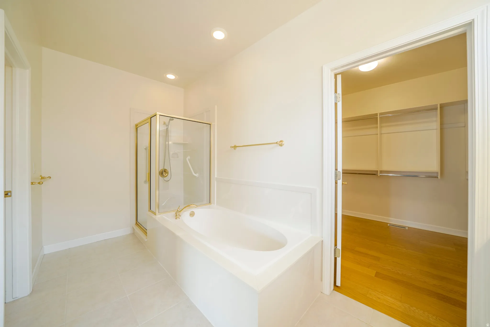 Full bath with a stall shower, a garden tub, light tile patterned floors, a walk in closet, and recessed lighting