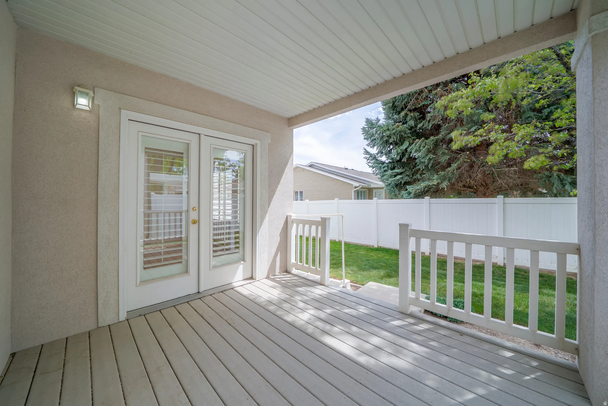 Wooden deck with french doors and a fenced backyard