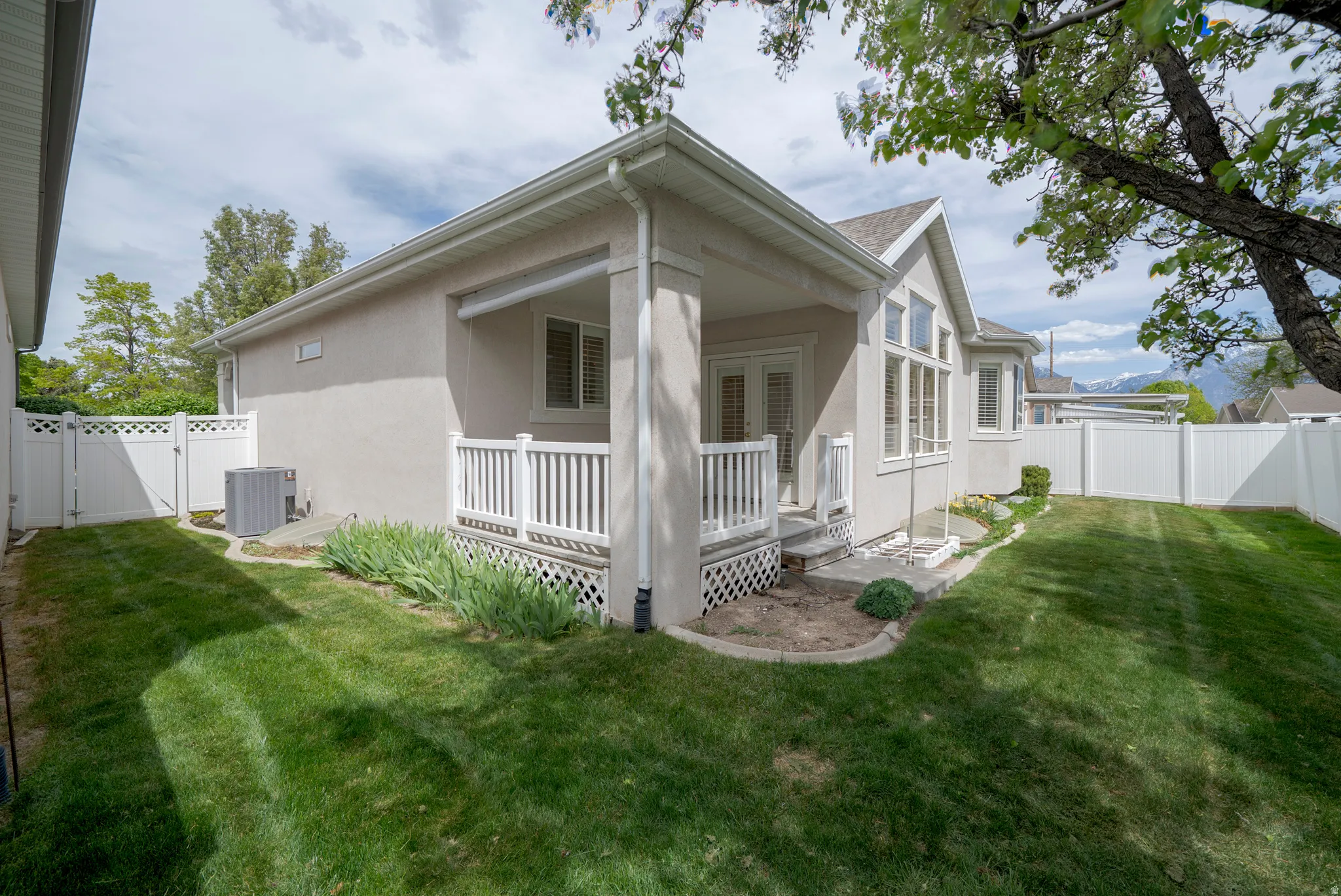 Rear view of house with a fenced backyard, a gate, and stucco siding