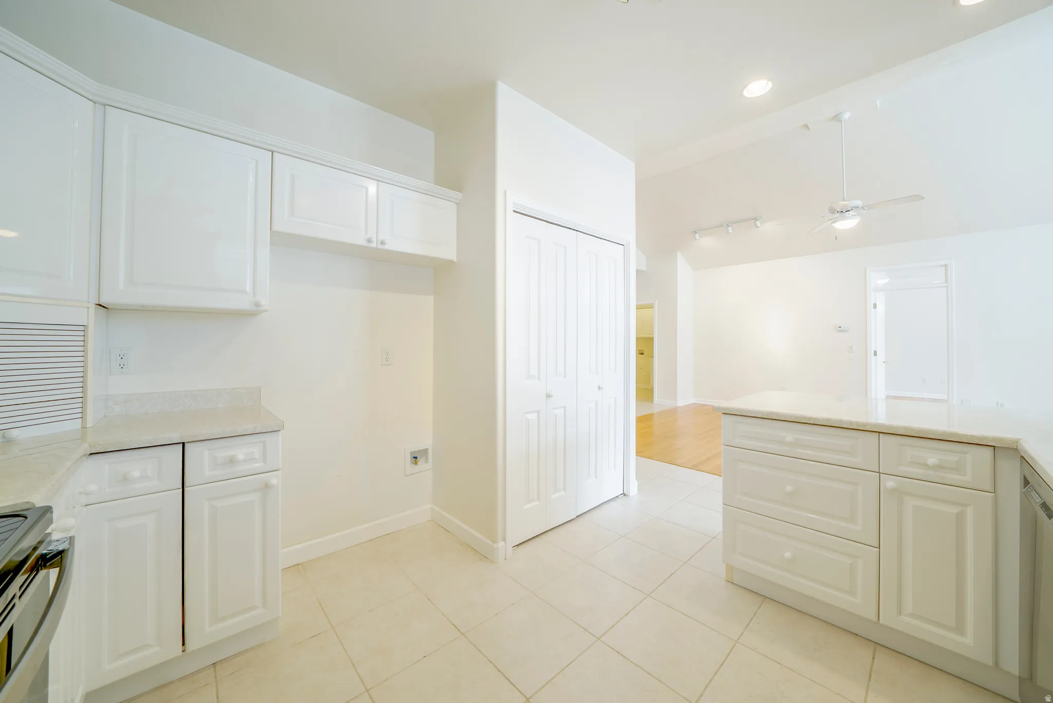 Kitchen featuring stainless steel range oven, ceiling fan, light stone countertops, white cabinetry, and lofted ceiling