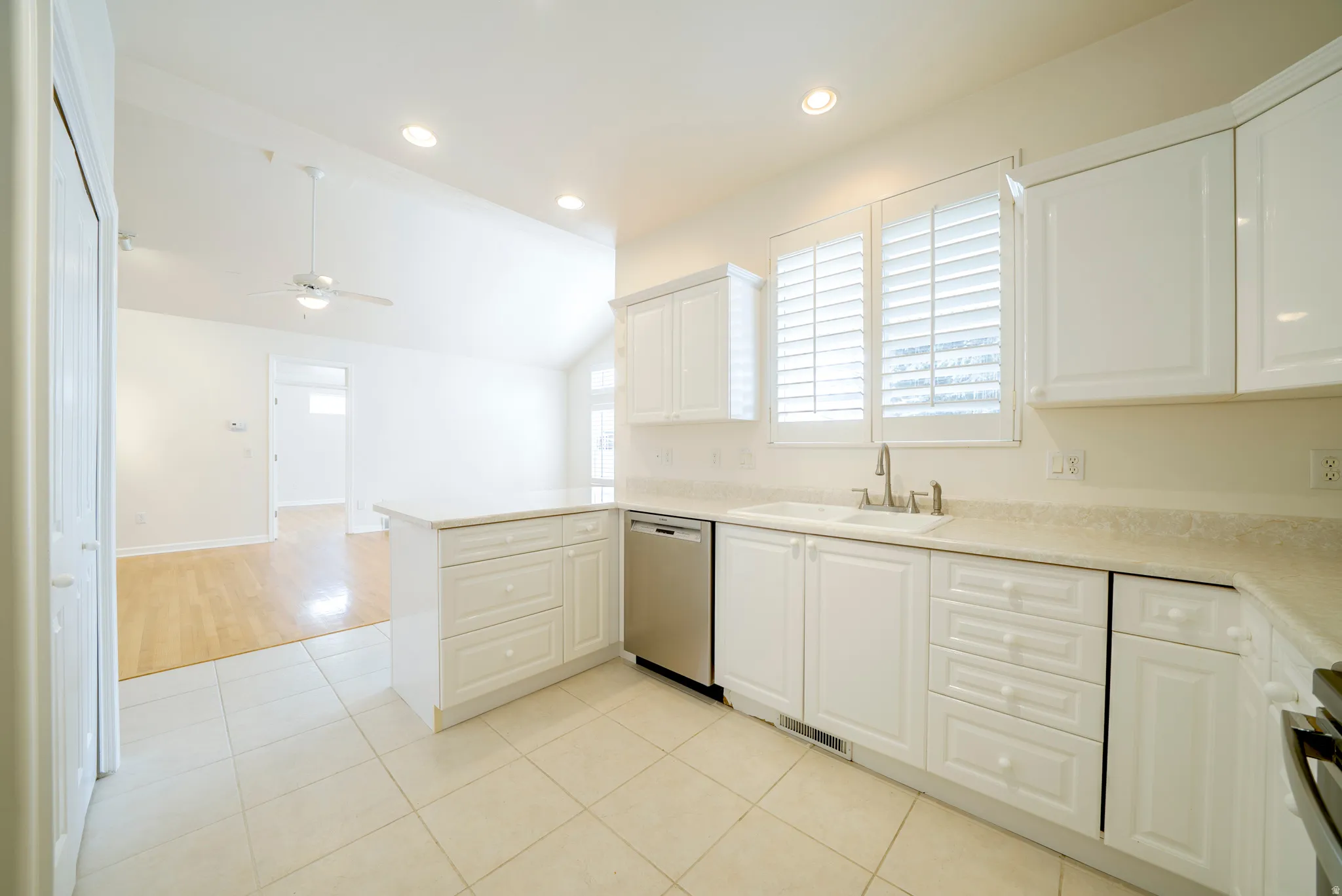 Kitchen featuring light countertops, stainless steel appliances, vaulted ceiling, white cabinetry, and recessed lighting