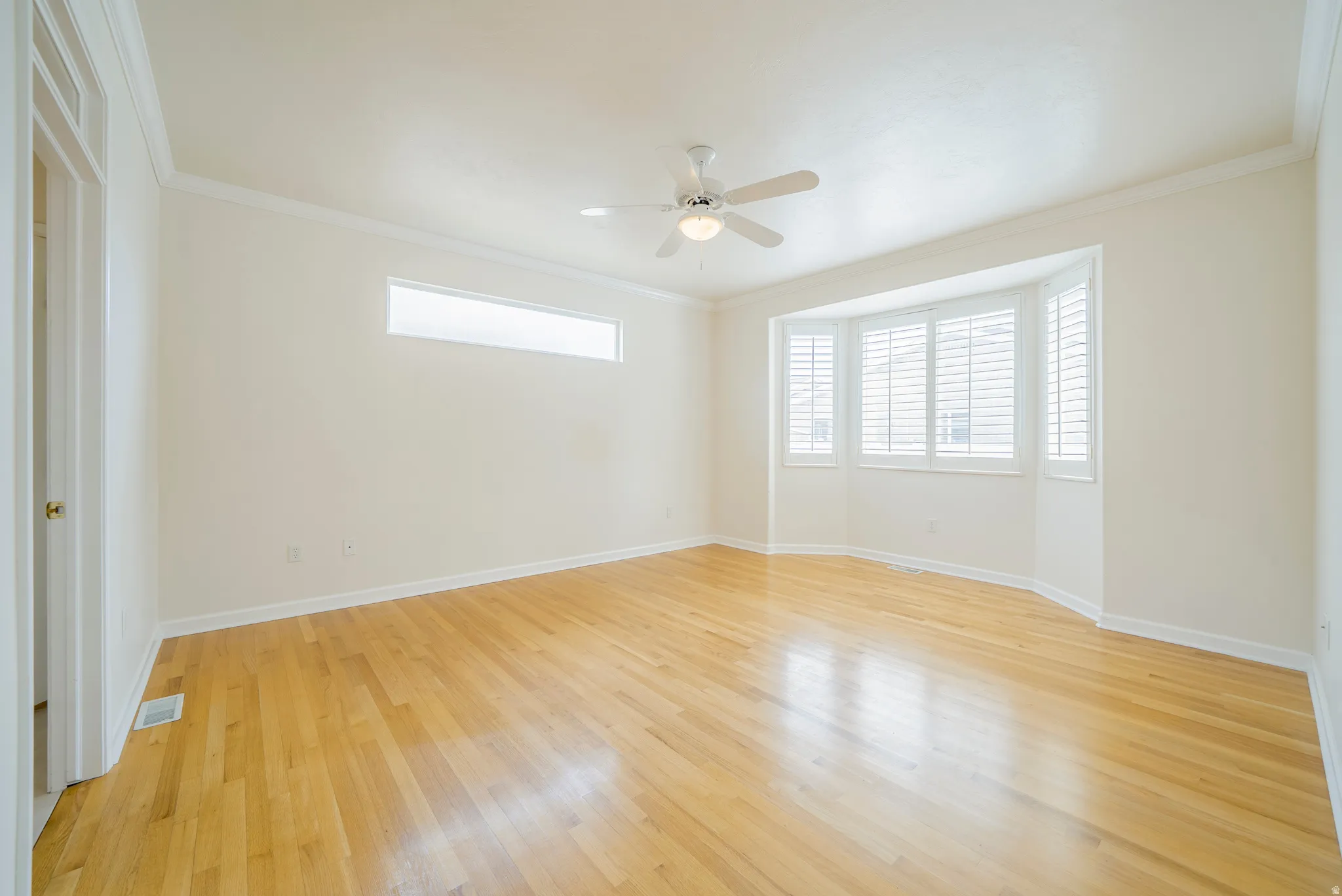 Spare room with light wood-style flooring, ceiling fan, ornamental molding, and plenty of natural light