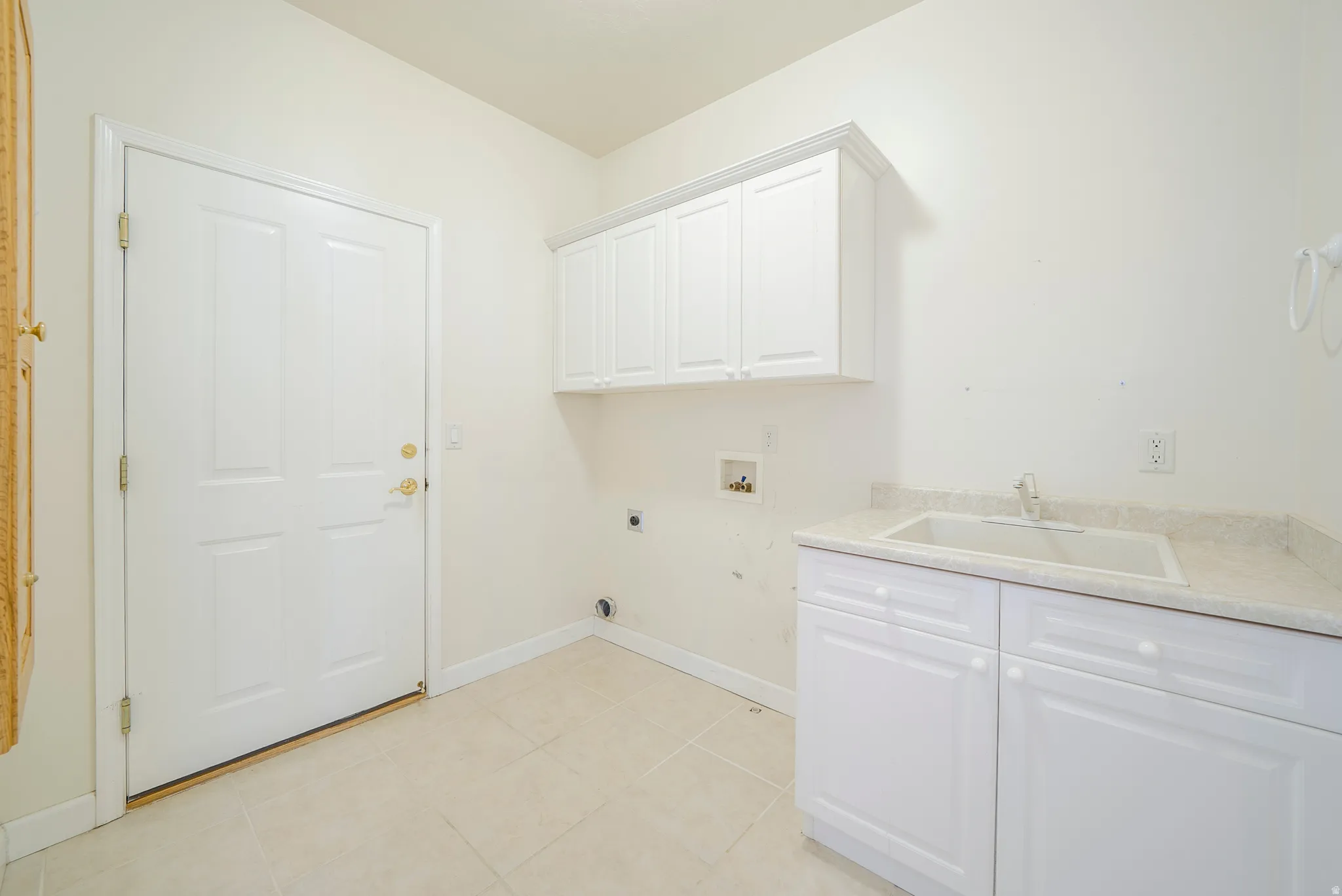 Laundry room featuring cabinet space, hookup for an electric dryer, hookup for a washing machine, and light tile patterned floors