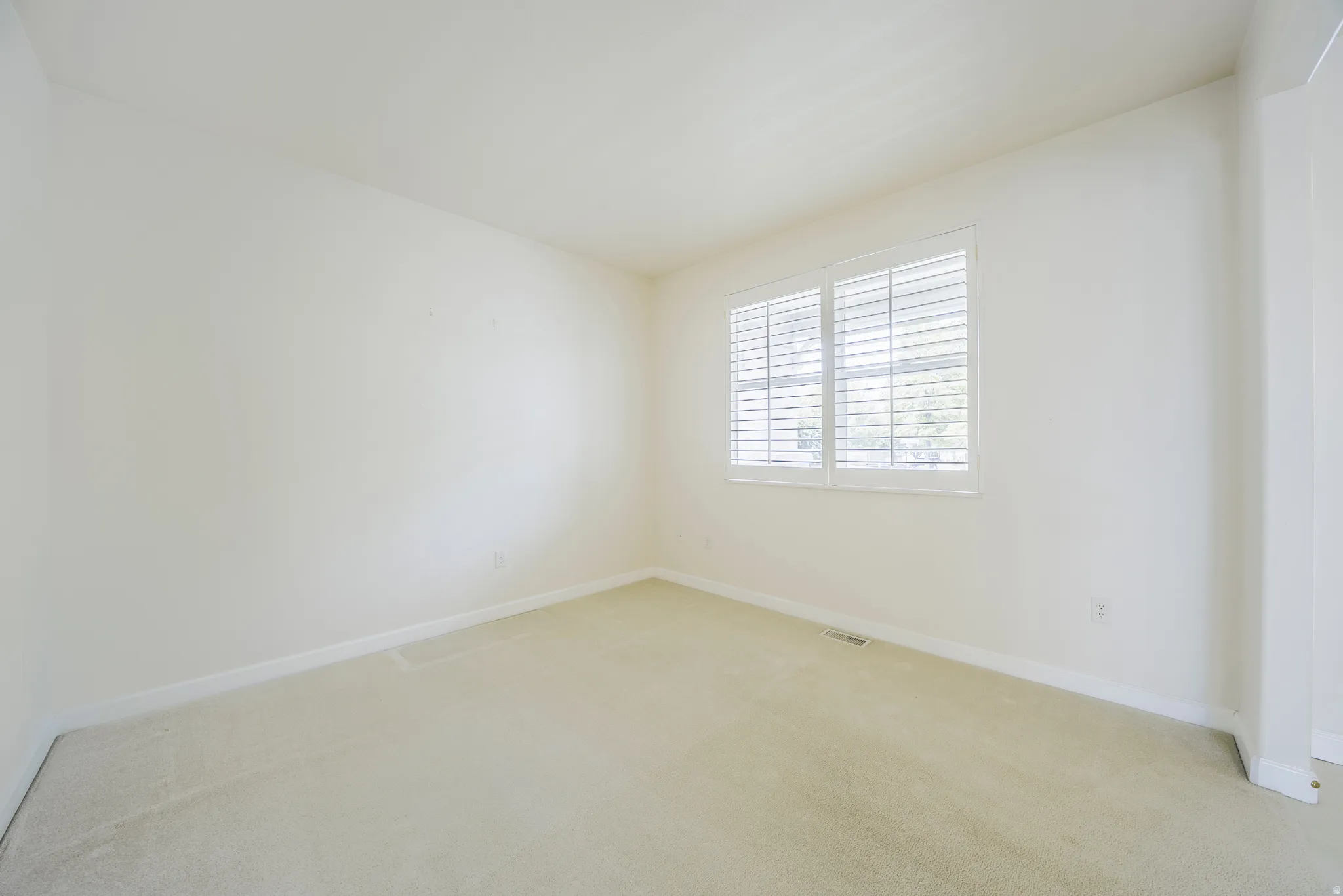 Spare room featuring light carpet and baseboards