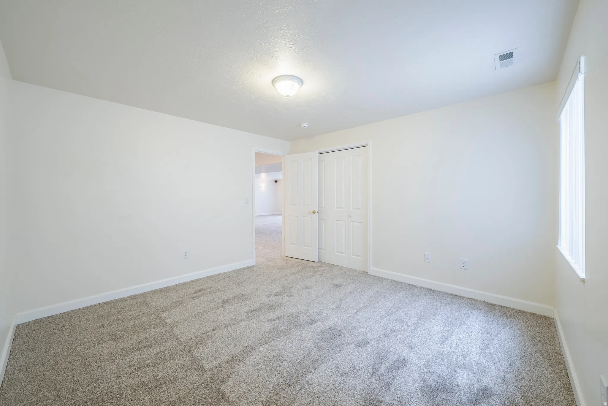 Unfurnished bedroom with light colored carpet, a closet, and multiple windows