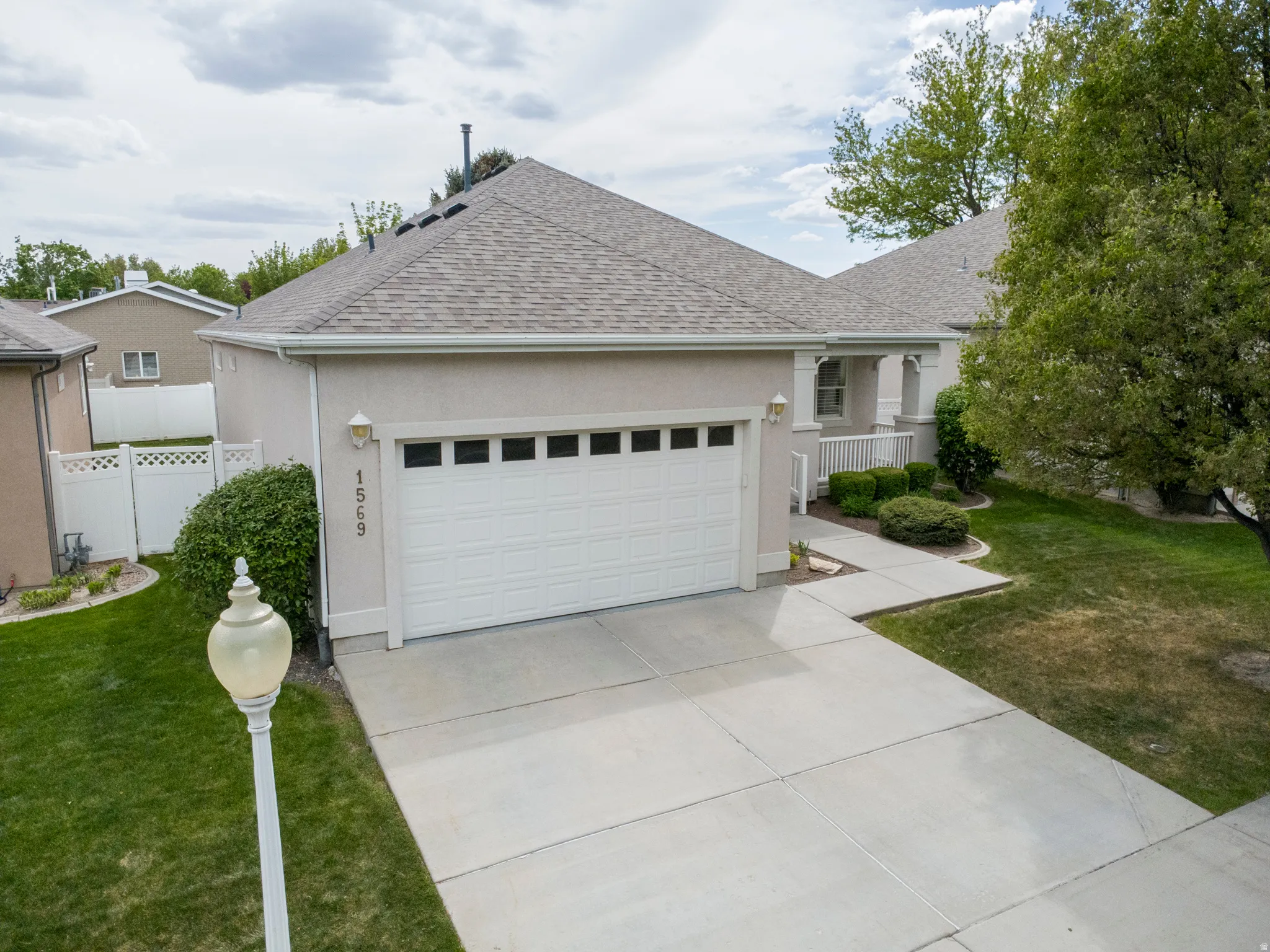 View of front of home with roof with shingles, stucco siding, a garage, and concrete driveway