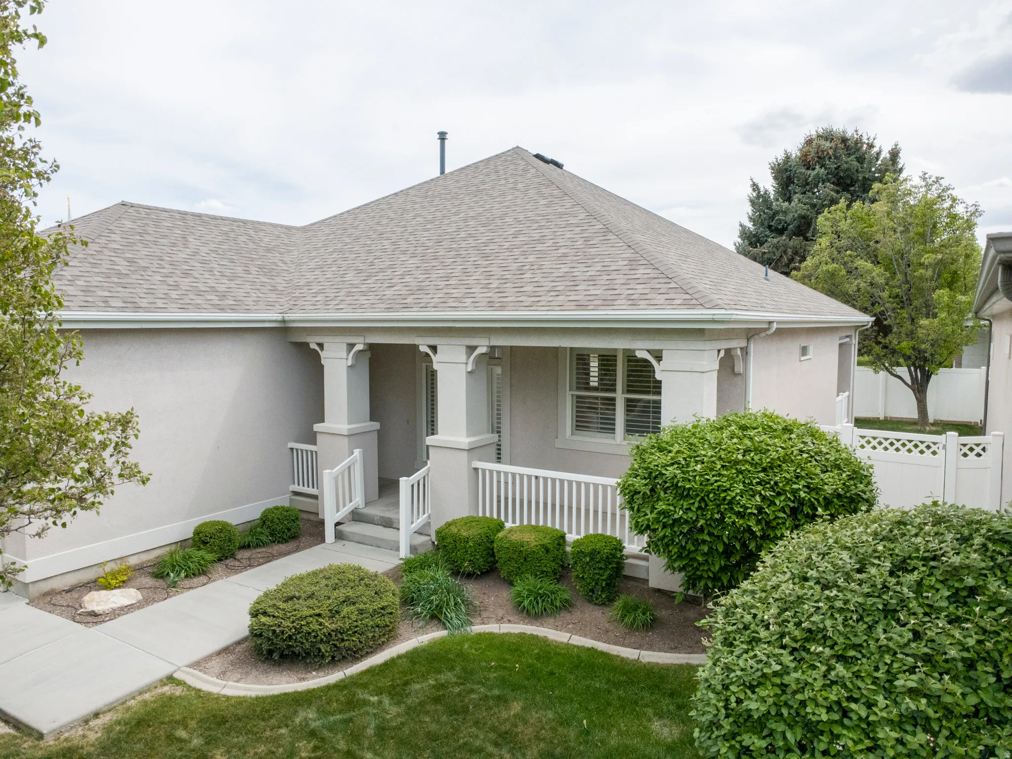 View of front of property featuring a shingled roof, stucco siding, and a porch