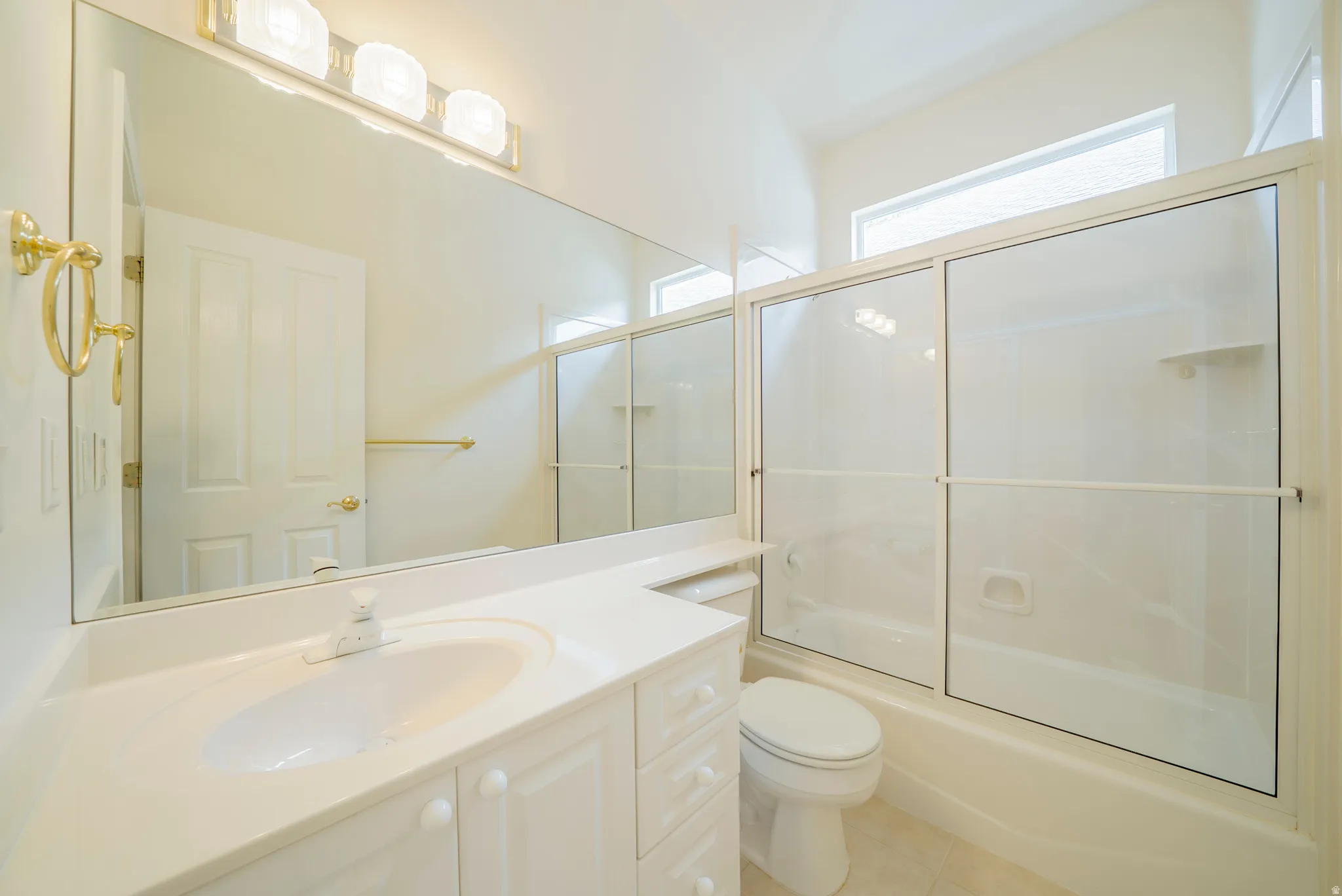 Bathroom with vanity, combined bath / shower with glass door, and light tile patterned floors