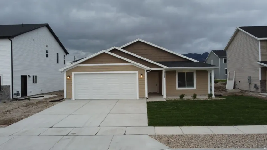 View of front facade featuring driveway, a garage, and a front lawn
