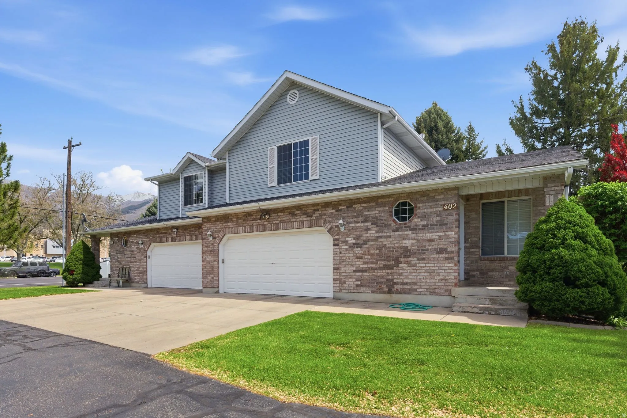 Traditional-style house featuring concrete driveway, an attached garage, brick siding, and a front lawn