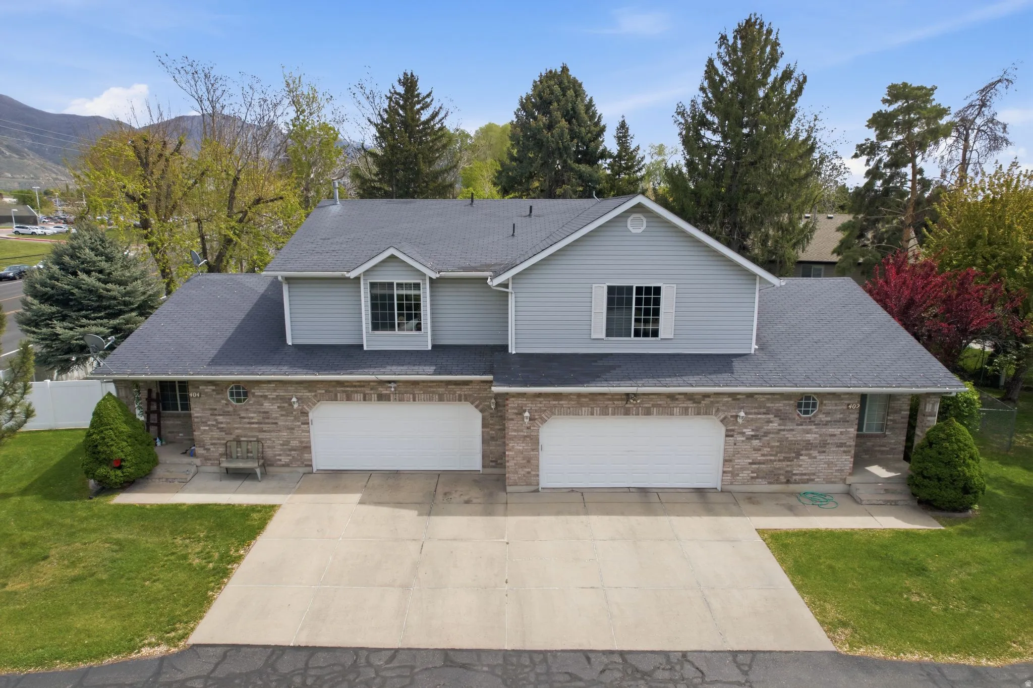 Traditional home with a garage, a mountain view, concrete driveway, and a front lawn