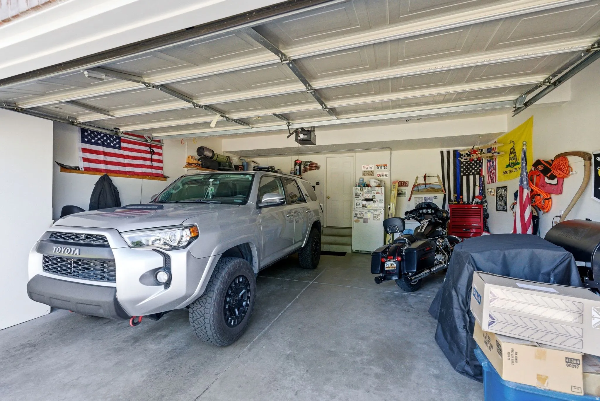 Spacious garage featuring a concrete floor, overhead lighting, and a white access door