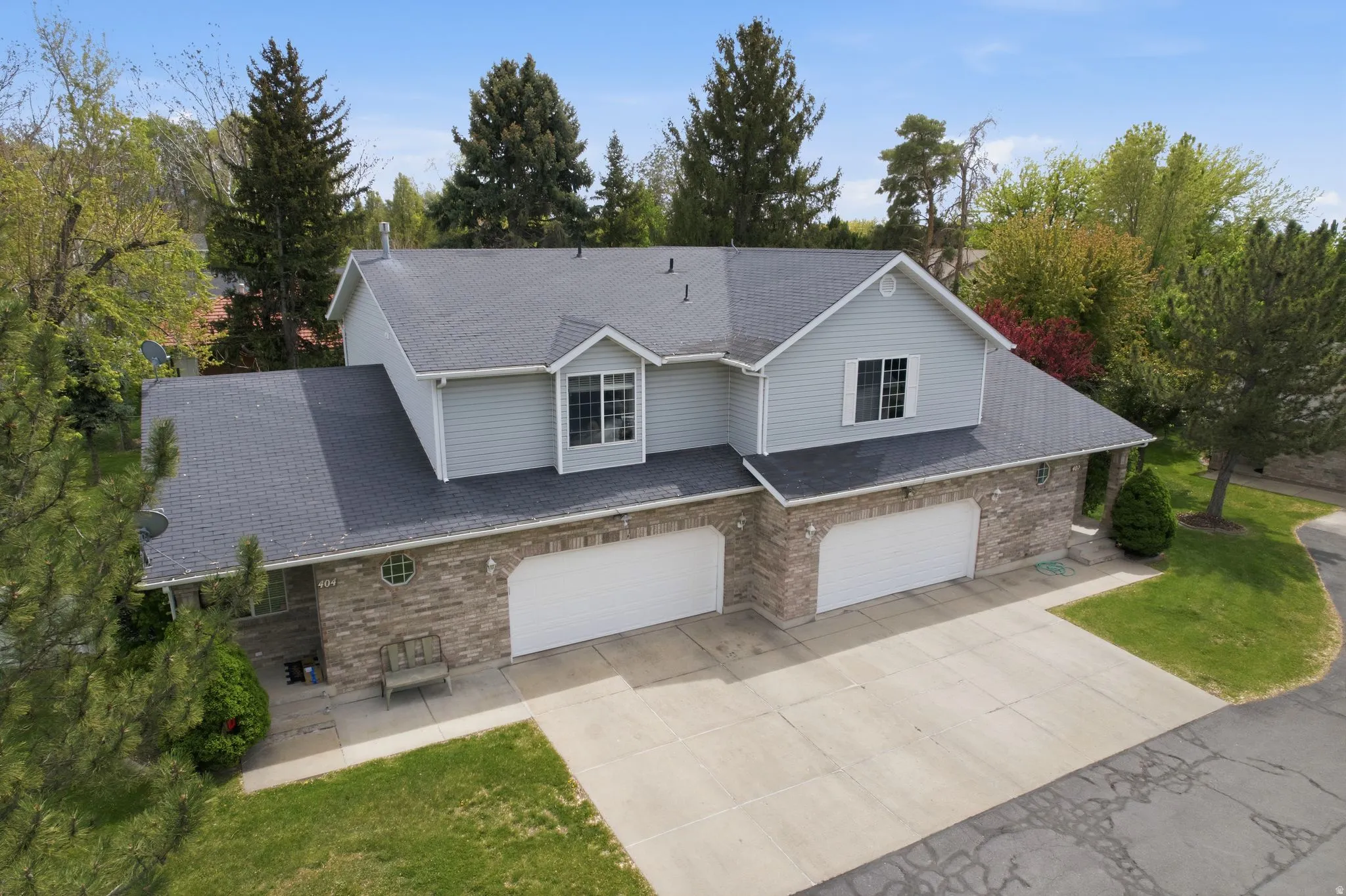 Traditional-style home with a garage, driveway, a front yard, and brick siding