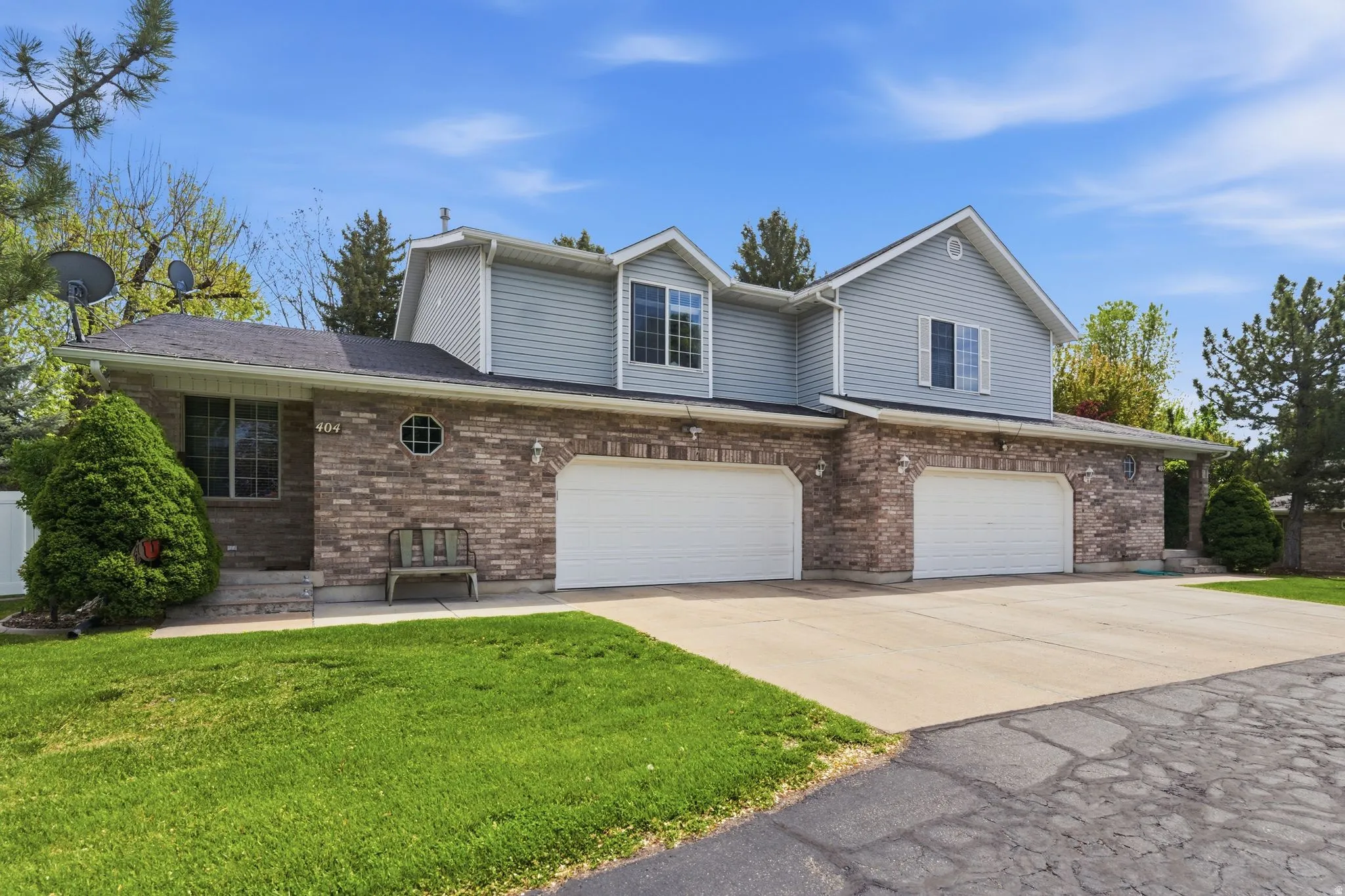 Traditional-style house featuring a garage, driveway, a front yard, and brick siding