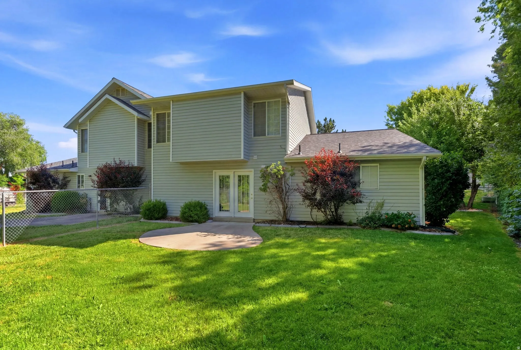 Rear exterior featuring light-colored horizontal siding, dual-pane windows, and a concrete patio