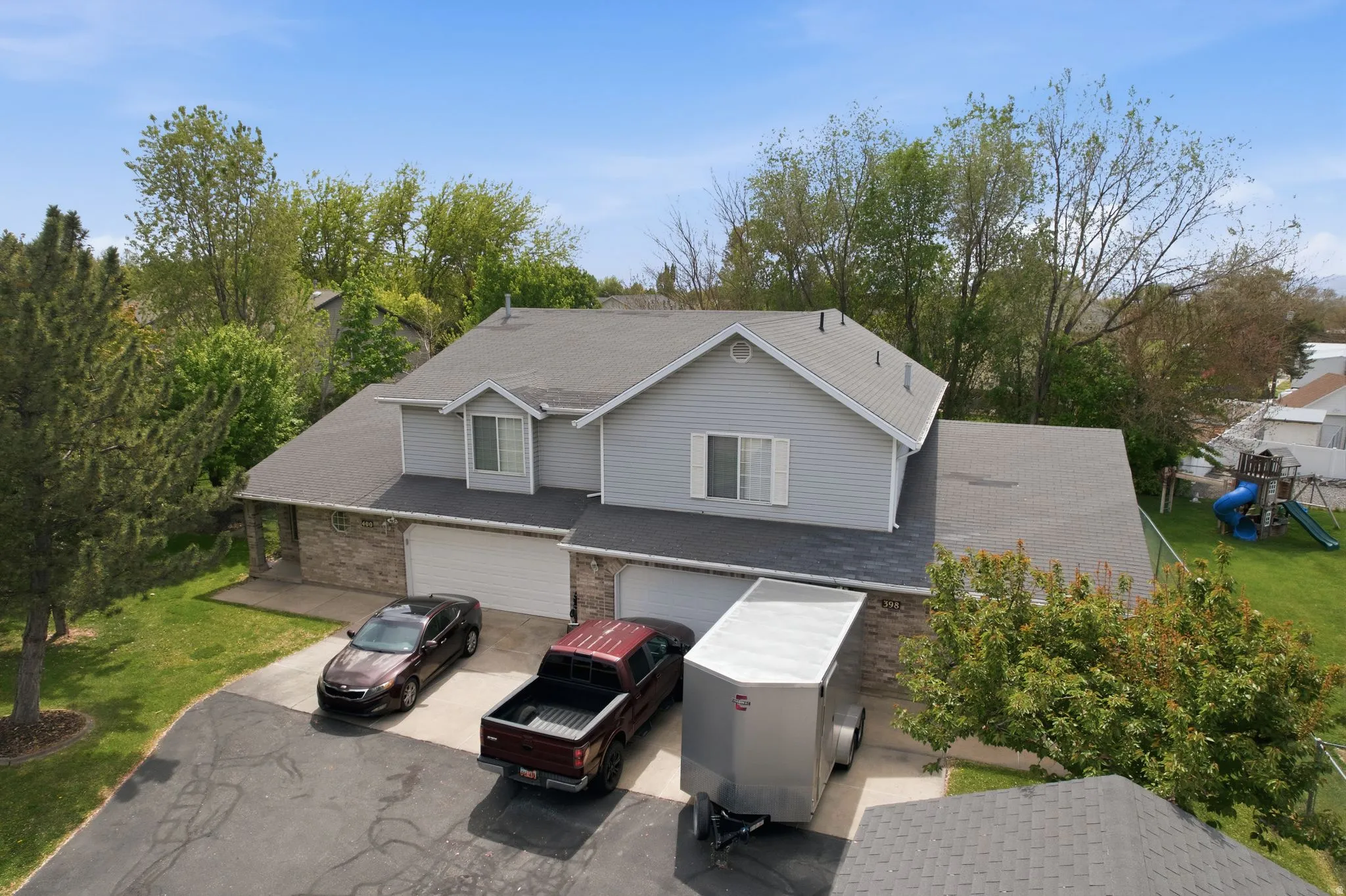 Traditional-style home with an attached garage, a front yard, a playground, asphalt driveway, and roof with shingles