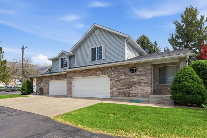 Traditional-style house featuring concrete driveway, an attached garage, brick siding, and a front lawn