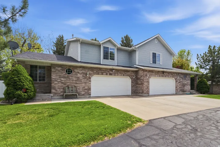Traditional-style house featuring a garage, driveway, a front yard, and brick siding