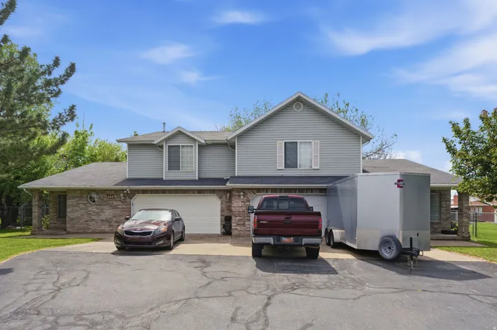 Traditional-style house with an attached garage, brick siding, driveway, and a shingled roof