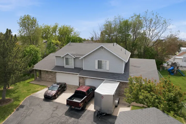 Traditional-style home with an attached garage, a front yard, a playground, asphalt driveway, and roof with shingles