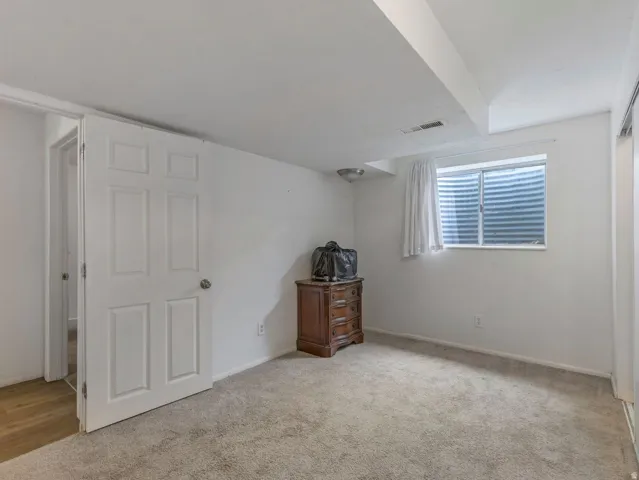 Unfurnished bedroom with light carpet and baseboards