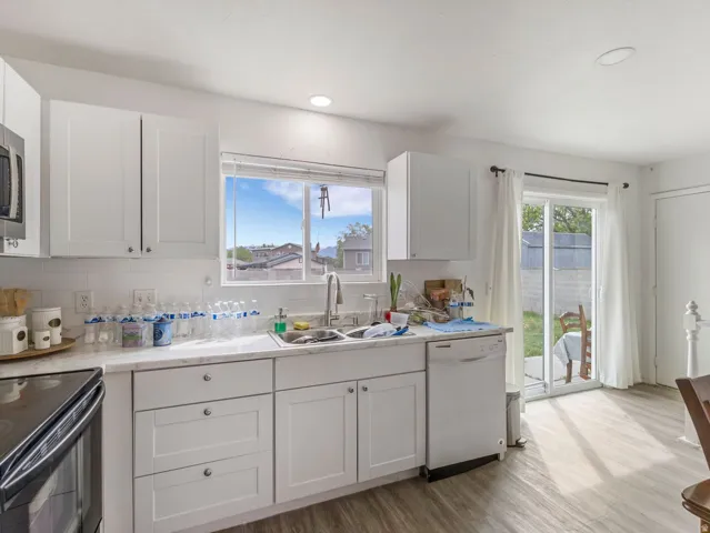 Kitchen featuring white cabinetry, dishwasher, light wood finished floors, tasteful backsplash, and black range with electric cooktop
