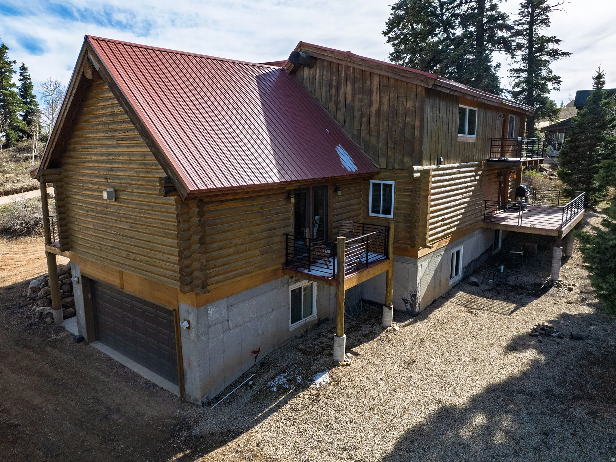 View of property exterior featuring a garage, a wooden deck, log siding, and a balcony