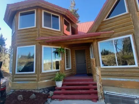 Log-style exterior featuring a red metal roof and white-framed windows