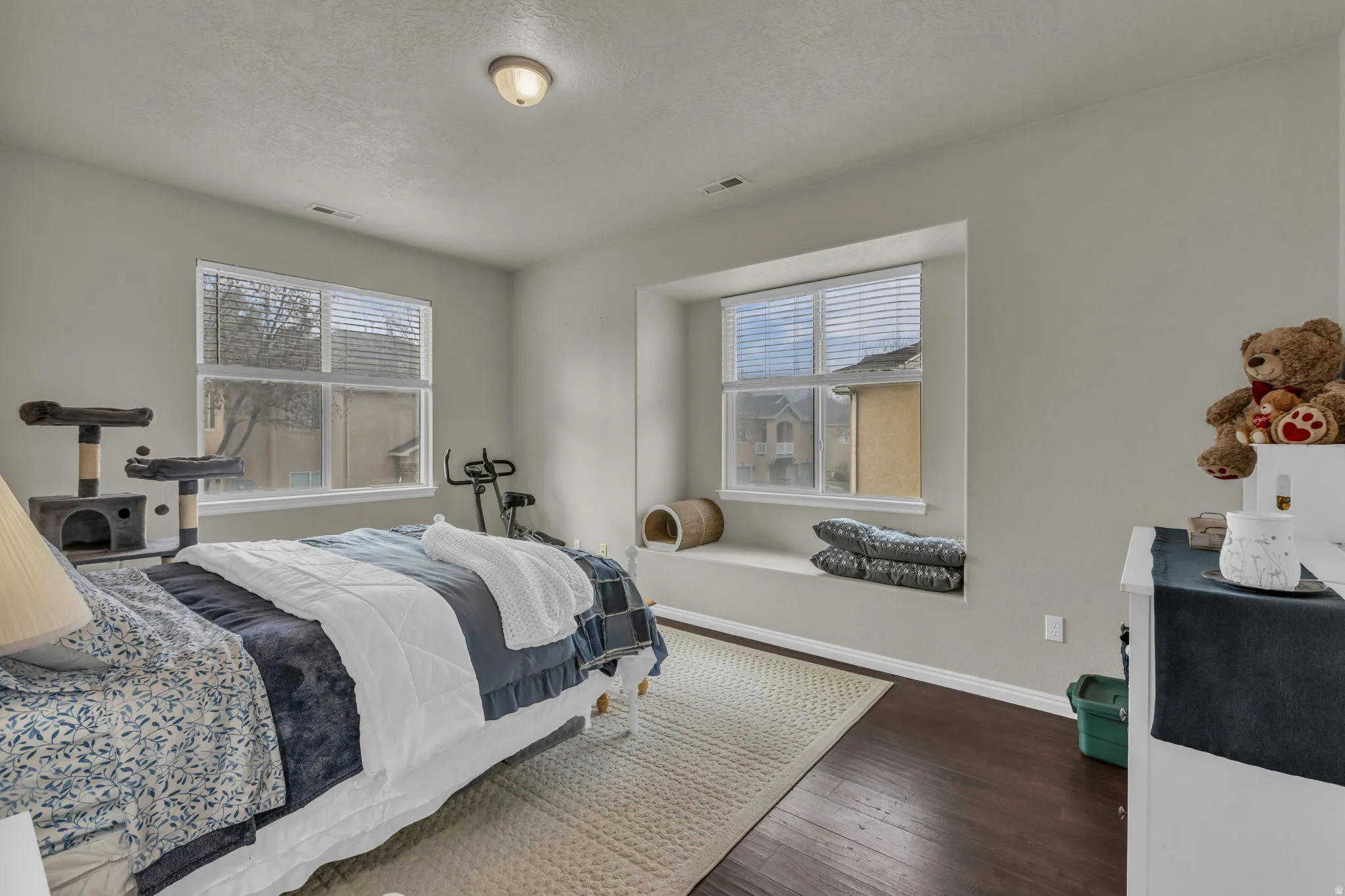 Bedroom featuring dark wood-type flooring, a textured ceiling, and multiple windows