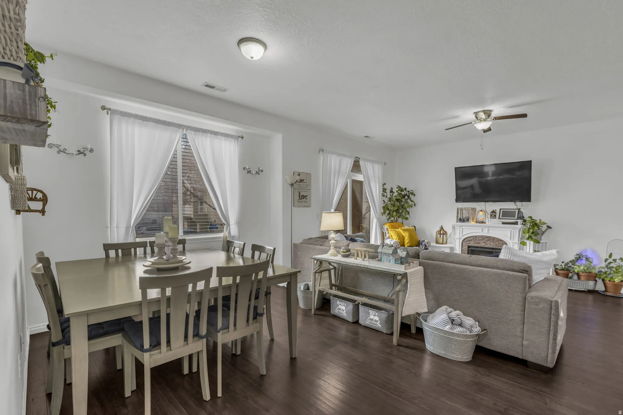 Dining room featuring dark wood-style floors, ceiling fan, and a fireplace
