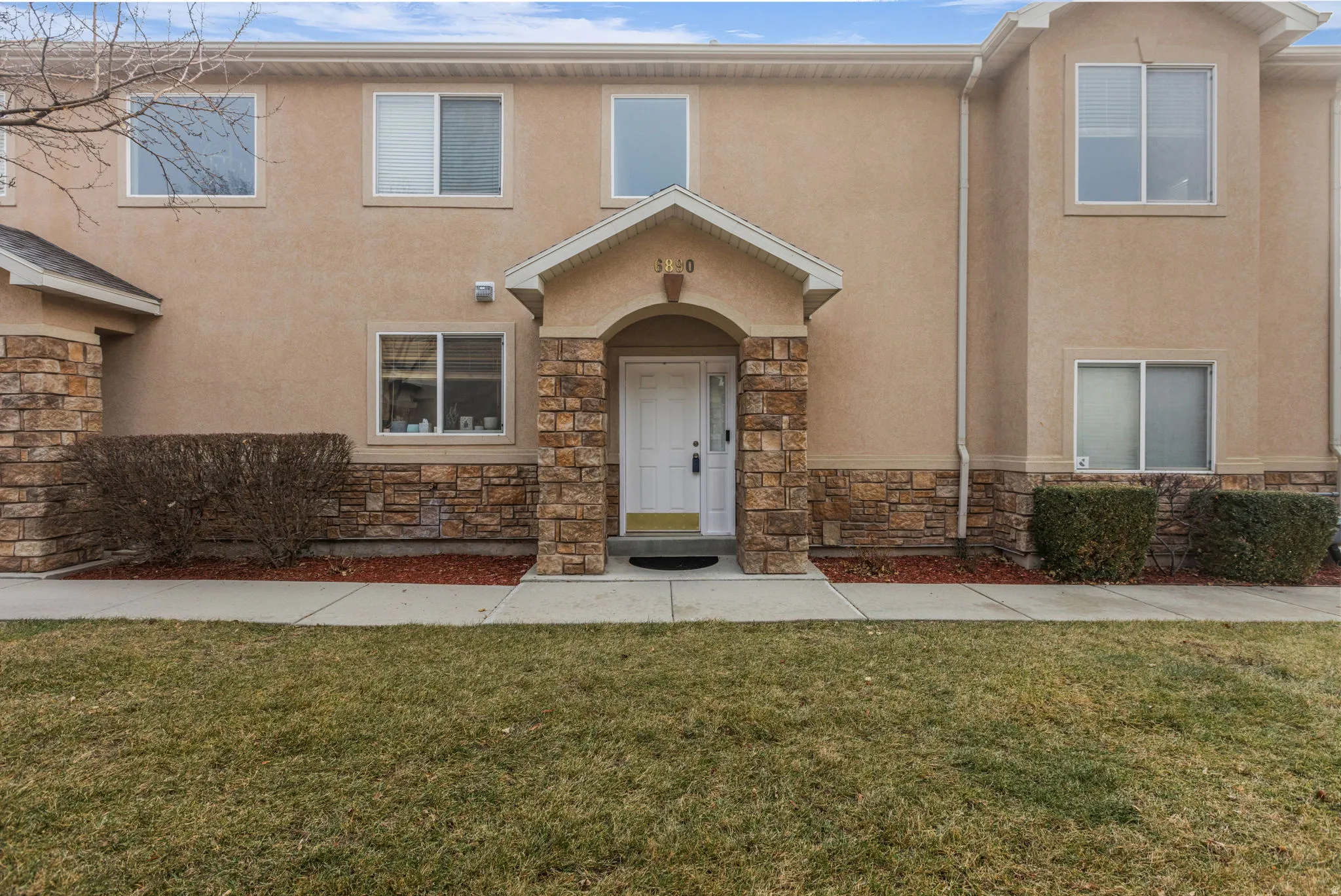 View of front of house featuring stone siding, stucco siding, and a front yard