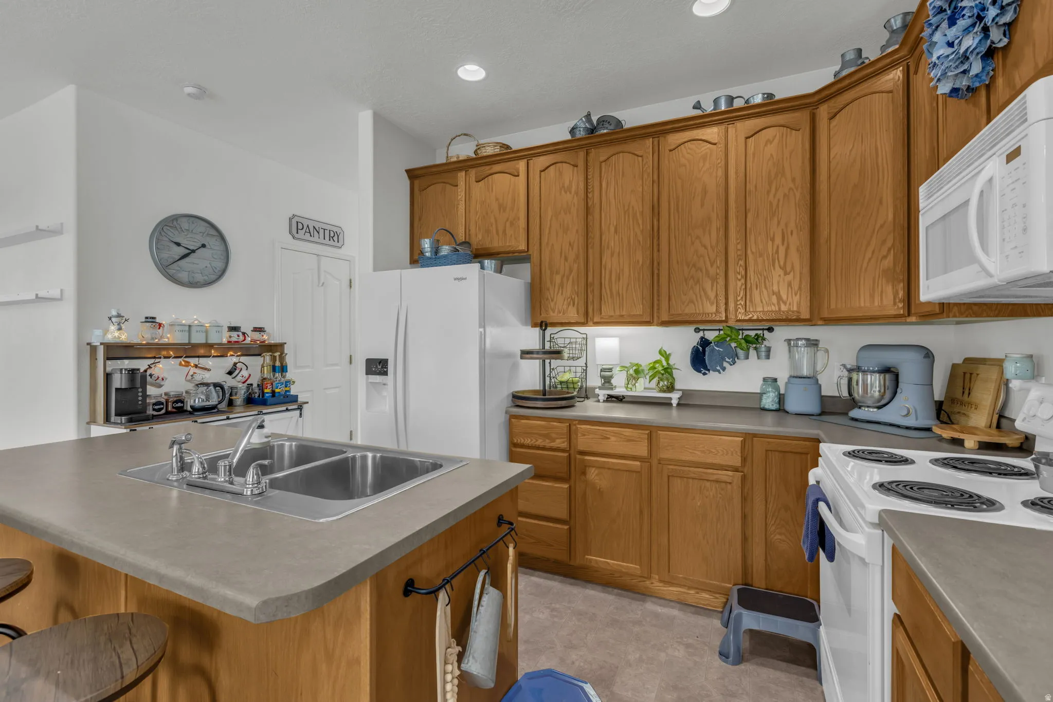 Kitchen with white appliances, wood finish cabinetry, a kitchen bar, and a kitchen island with sink