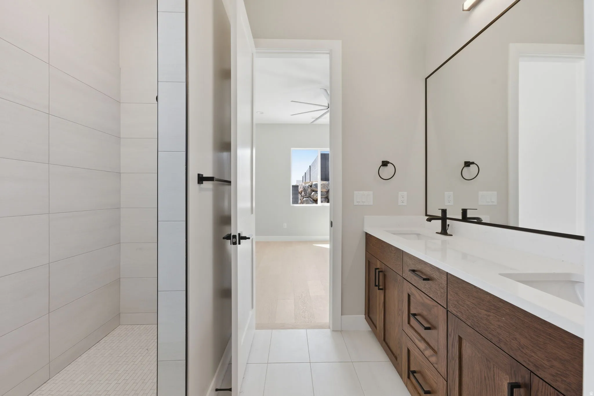 Full bathroom with double vanity, walk in shower, and light tile patterned floors