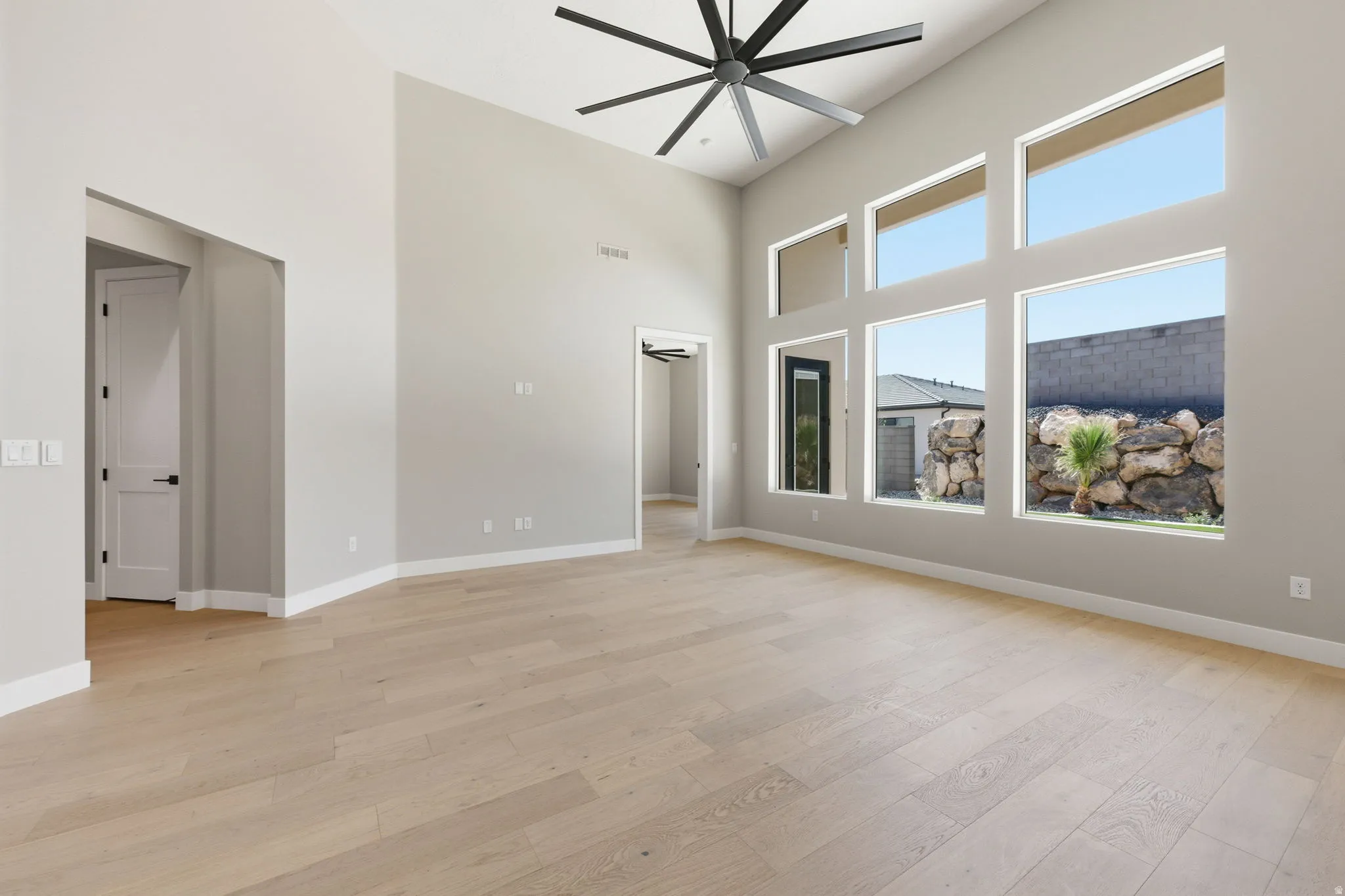 Unfurnished room with a high ceiling, a ceiling fan, and light wood-style floors