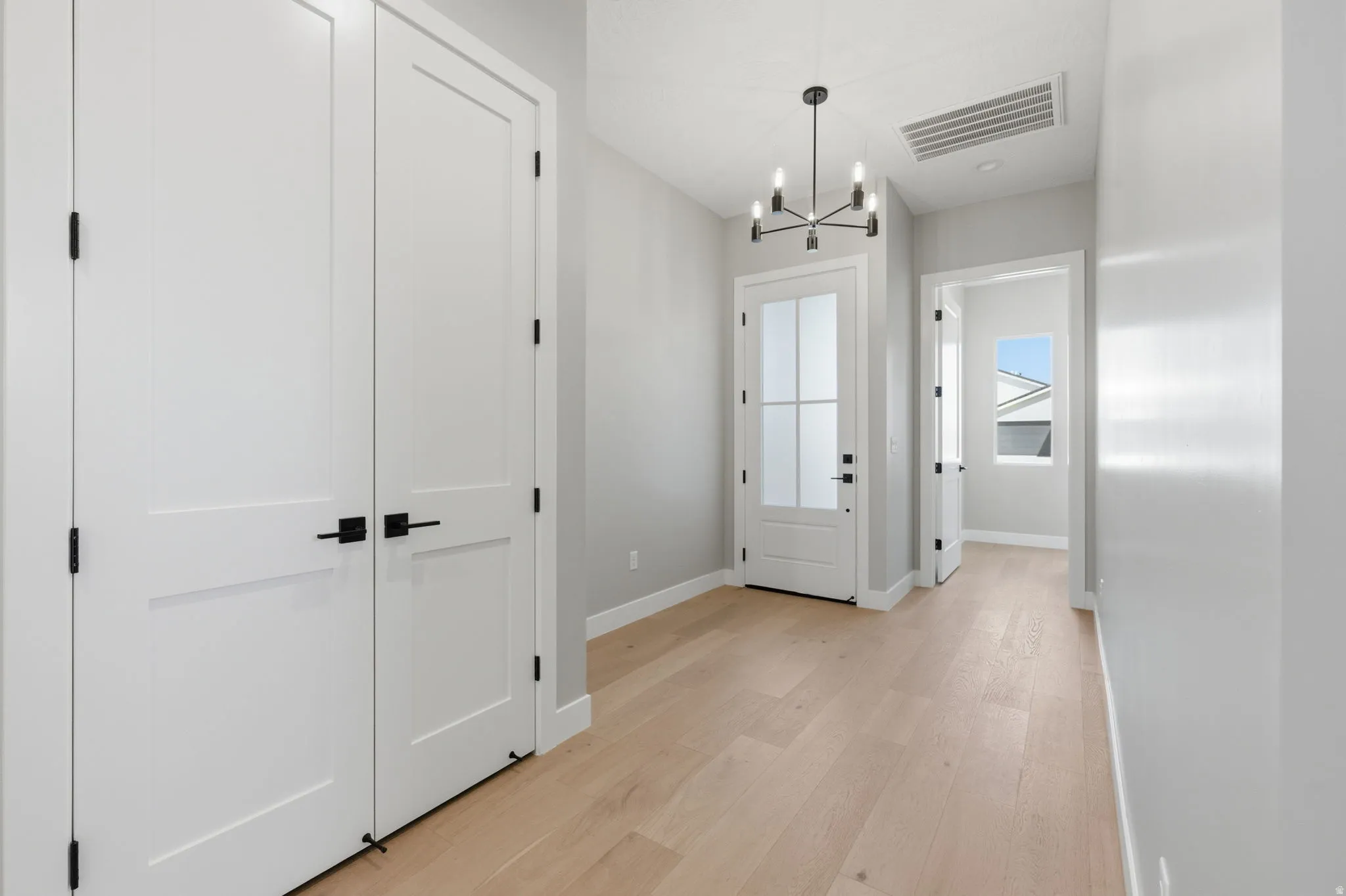 Foyer entrance with hanging lights and light wood finished floors
