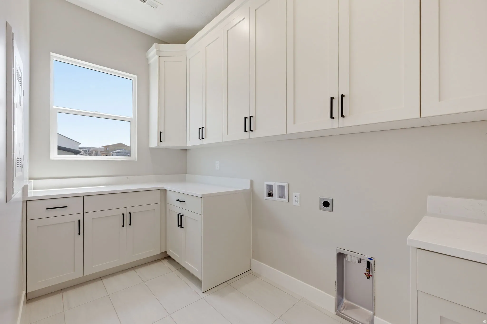 Laundry area featuring hookup for a washing machine, cabinet space, electric dryer hookup, and light tile patterned floors