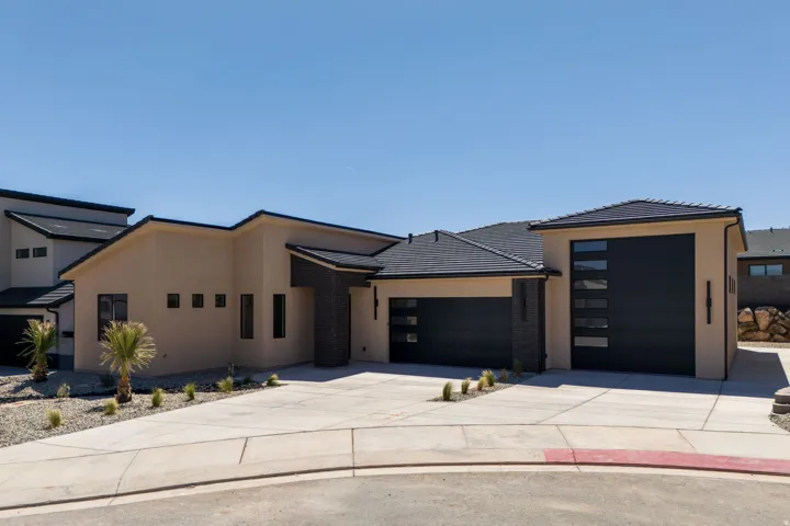 View of front of property featuring driveway, stucco siding, and an attached garage