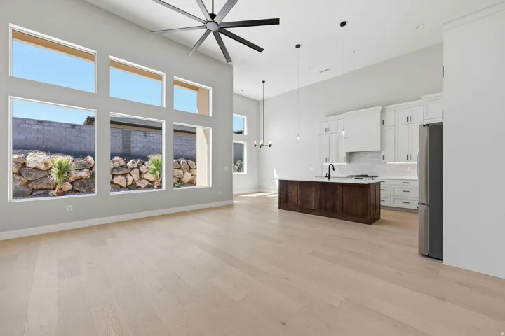 Dual tone kitchen featuring a high ceiling, a chandelier, a center island with sink, open floor plan, and freestanding refrigerator