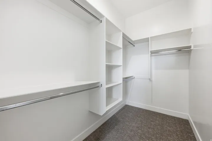 Walk in closet featuring dark colored carpet