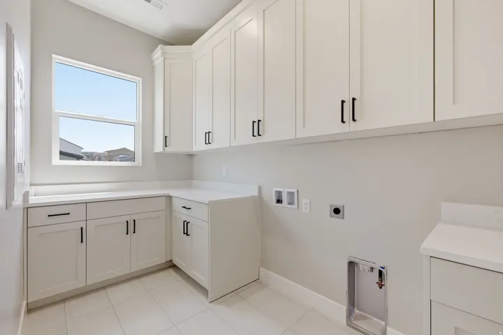 Laundry area featuring hookup for a washing machine, cabinet space, electric dryer hookup, and light tile patterned floors