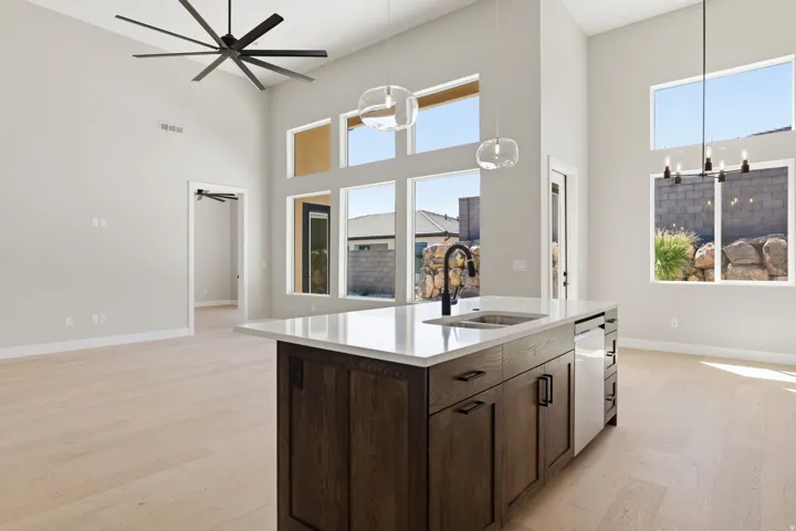 Kitchen with dark wood finish cabinets, a high ceiling, light wood-type flooring, hanging lights, and plenty of natural light