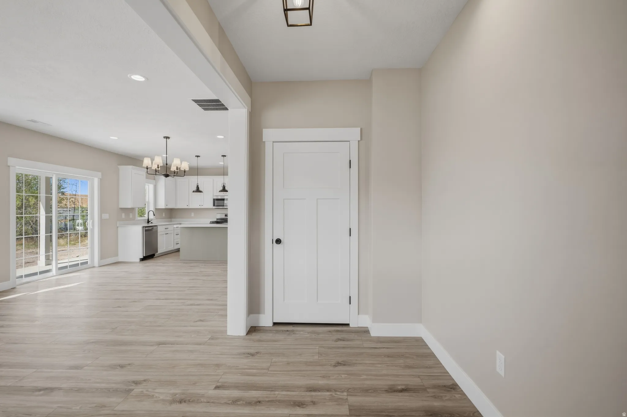 Hallway with hanging lights and light wood-style flooring