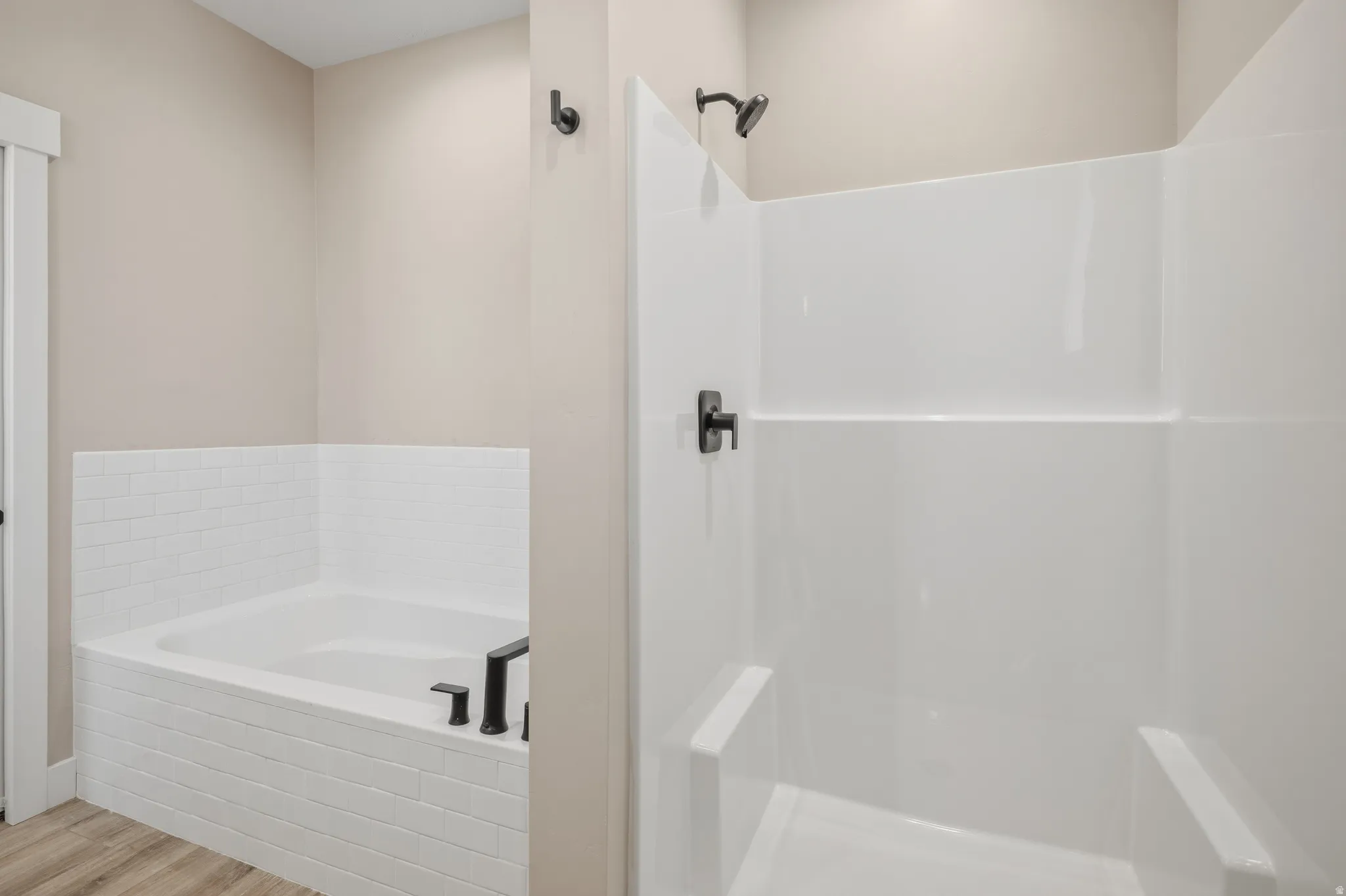 Bathroom with a bath, a walk in shower, and light wood-style floors
